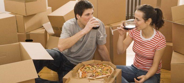 Pareja teniendo el vino y la pizza después de la transferencia de utilidades después de mudarse