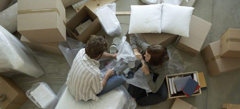 Couple surrounded by boxes packing, representing packing services