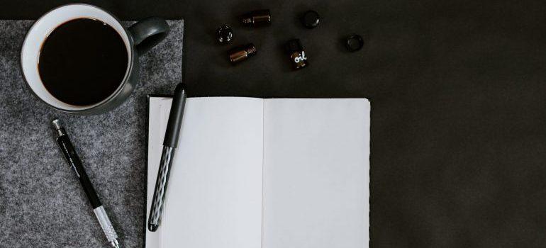 Cuaderno, bolígrafos y café sobre la mesa.