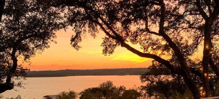 A view onto a lake and trees at sunset representing the summers after one's Austin relocation