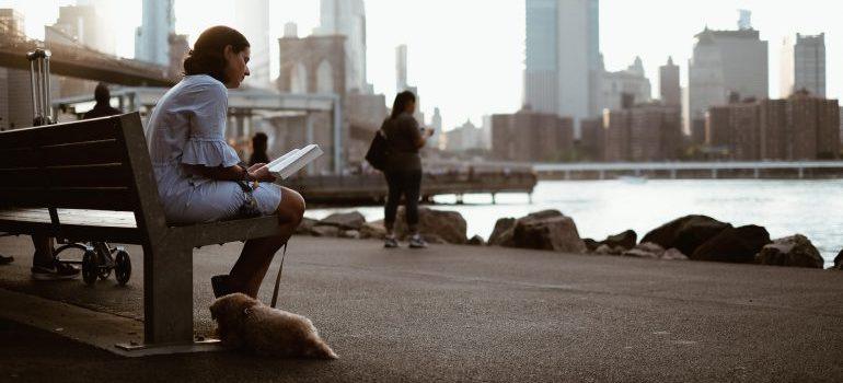 Una chica sentada en un banco con su cachorro inBrooklyn Parque del Puente de