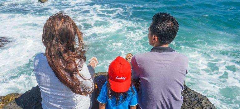 Una familia es relajante emplazamiento en la roca y mirando el océano. 