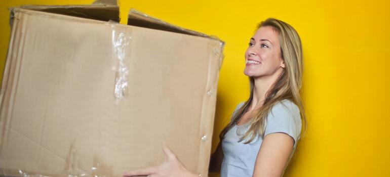 Una mujer cargando una caja de mudanza