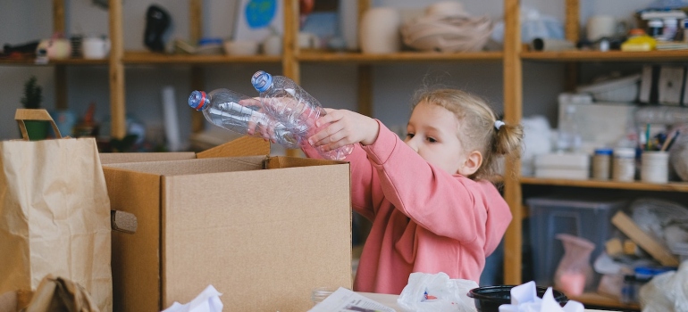 a girl putting plastic bottles in a box 