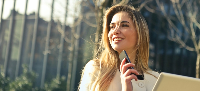 una mujer sonriendo y sosteniendo un teléfono